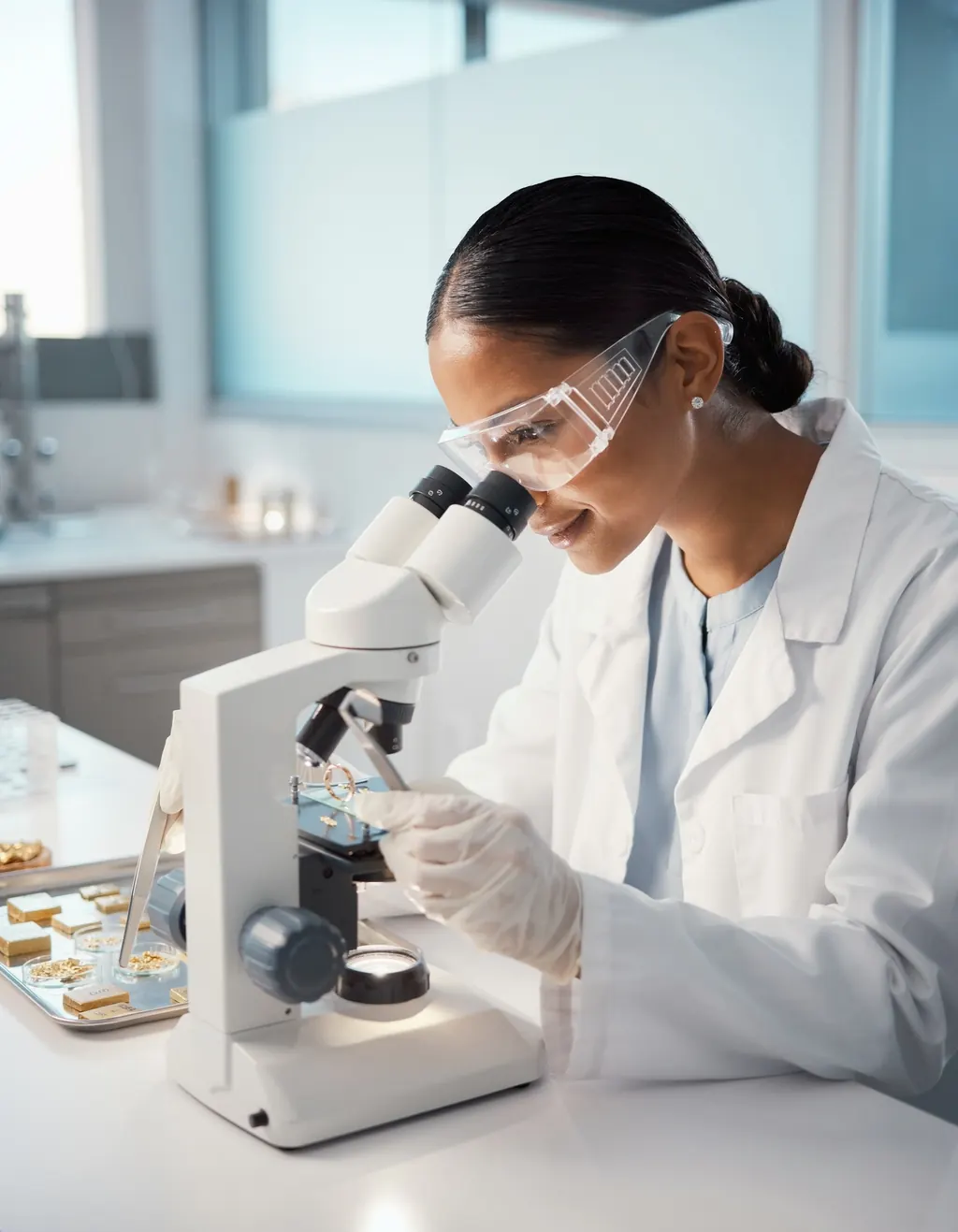 An appraiser in a lab coat examining a gold ring under a stereo microscope